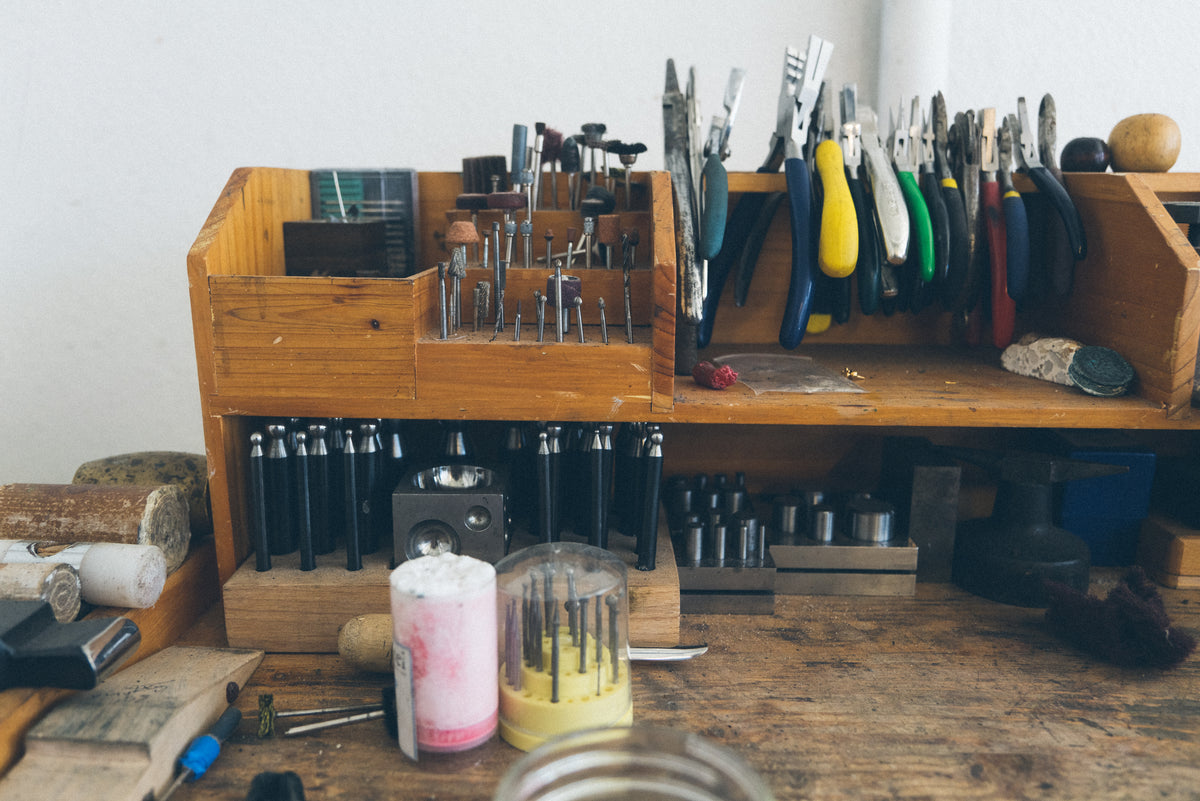 Hand tools and bench pins arranged on a jeweler’s workbench in the studio of Alexis Pavlantos